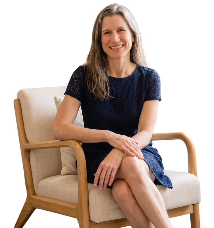 A smiling woman in a blue dress sitting in an armchair, offering mental wellness montclair family therapy support.